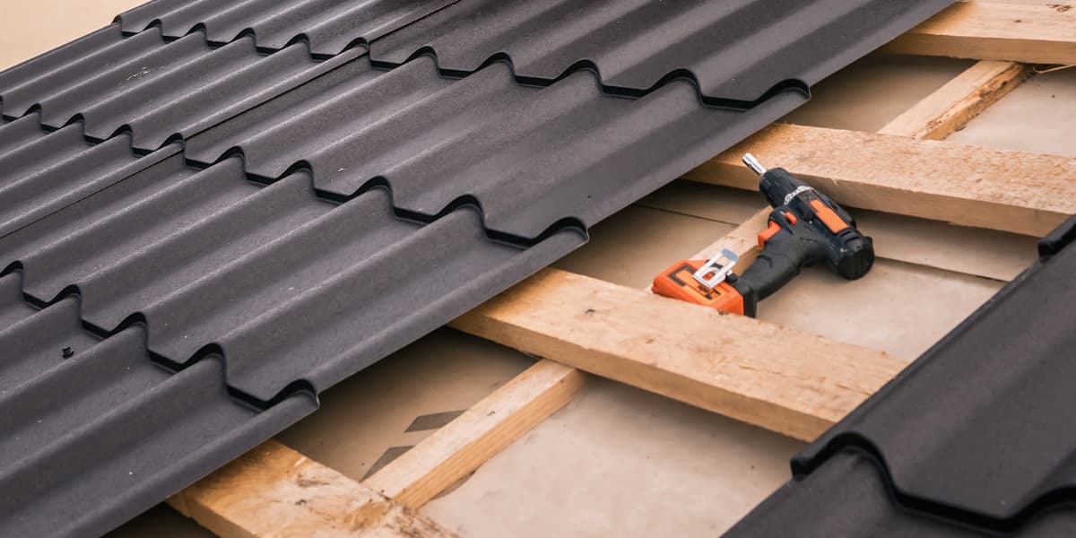 A roofing contractor skillfully hammers a metal roof into place, showcasing expertise in roof installation.