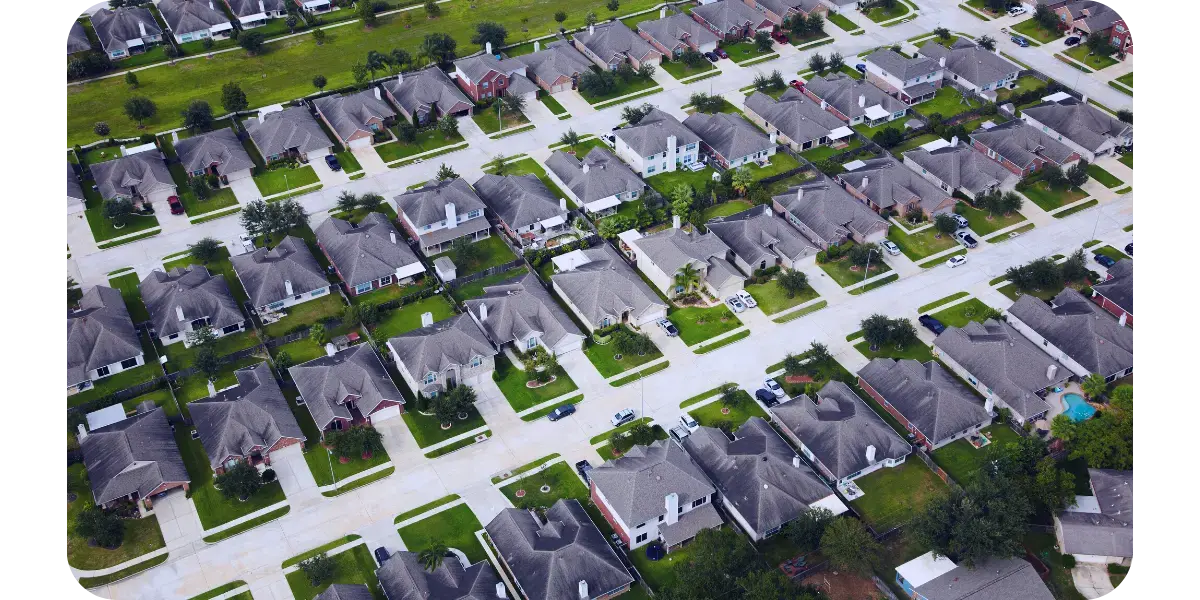 Aerial view of a neighborhood showcasing various houses, emphasizing efficient roofing solutions for cost savings.