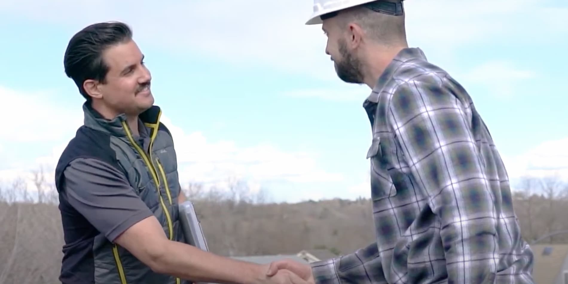 Two men shaking hands on a rooftop, symbolizing partnership in roofing sales with OneClick Code.